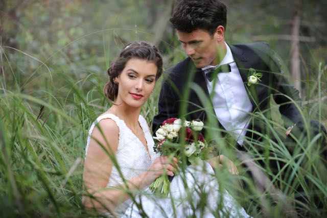 bride and groom sitting in grass