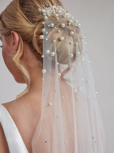 Ivory beaded bridal veil being worn oven over a bun hair style.